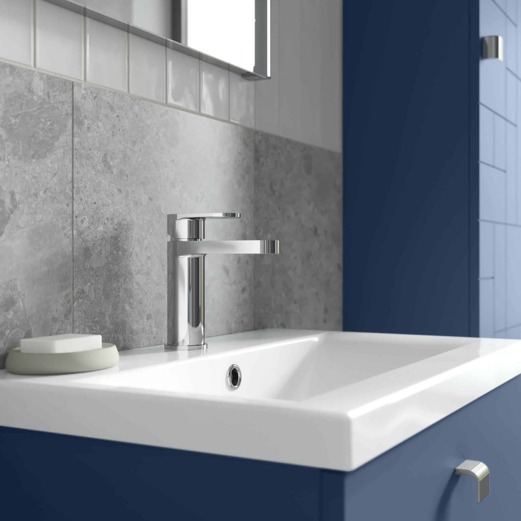 Sleek modern bathroom sink with chrome faucet and blue cabinetry, featuring grey tiled backsplash and minimalist design. Perfect for contemporary bathroom renovation.