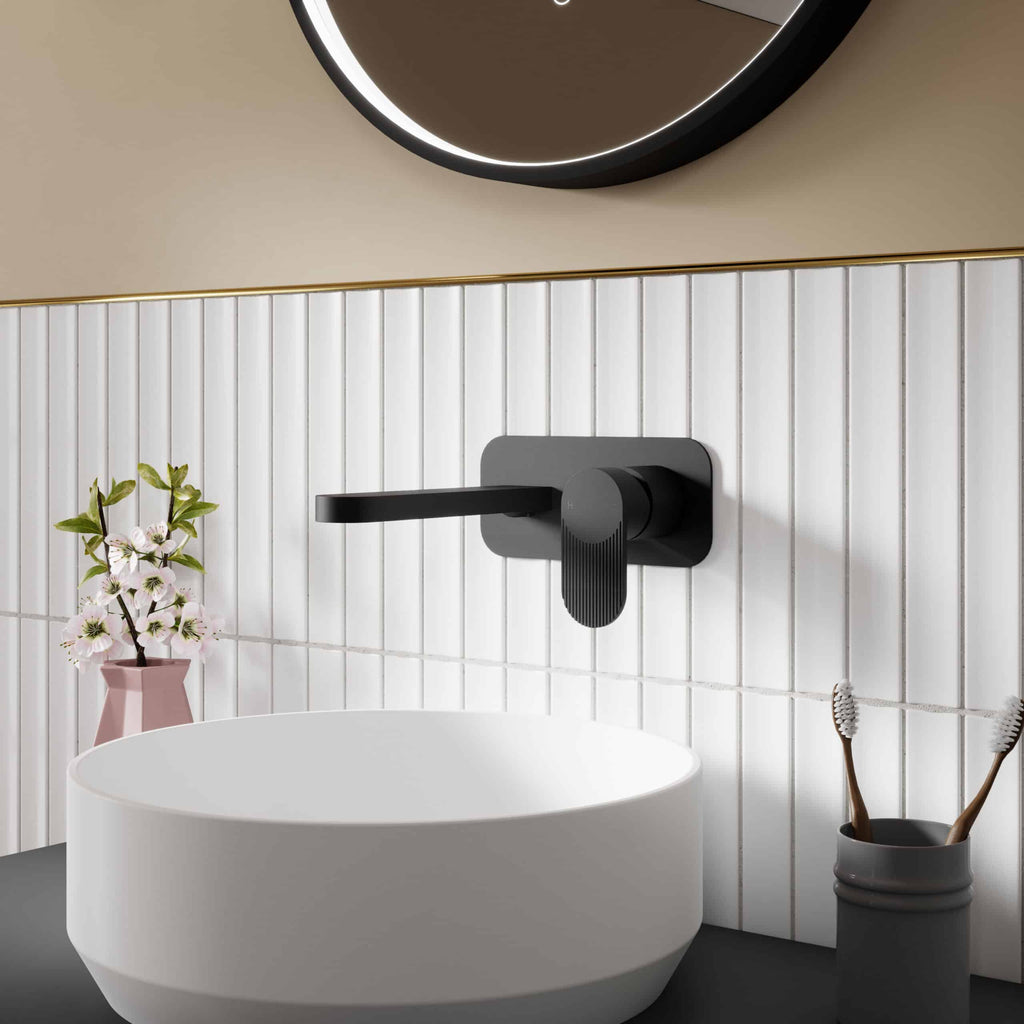 Sleek black bathroom tap with matte finish on white tiled wall, modern bathroom decor with round mirror, vase with flowers, and toothbrush holder, emphasizing contemporary stylish bathroom fixtures.