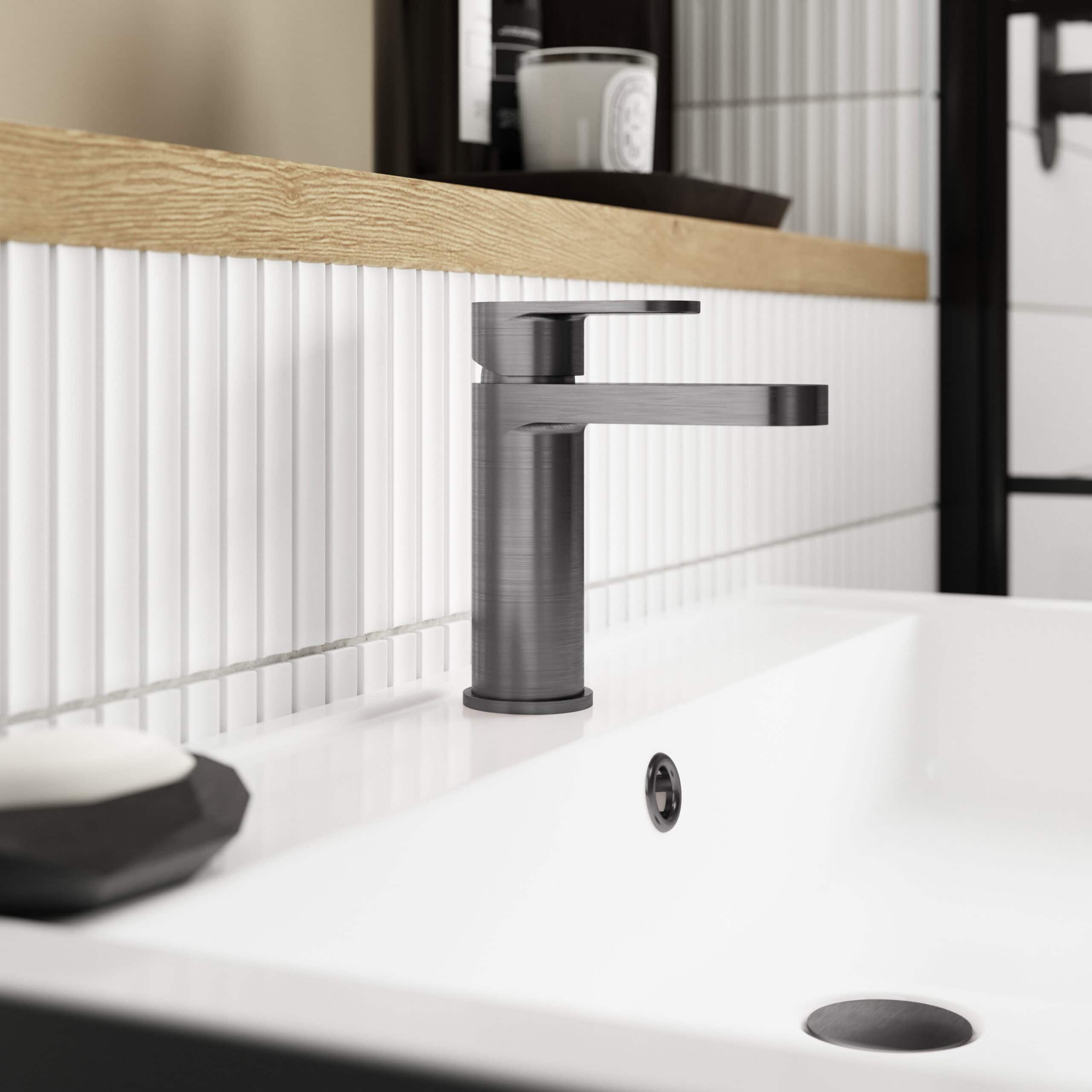 Brushed nickel bathroom sink faucet installed on a modern white ceramic washbasin with wall-mounted tiled backsplash.