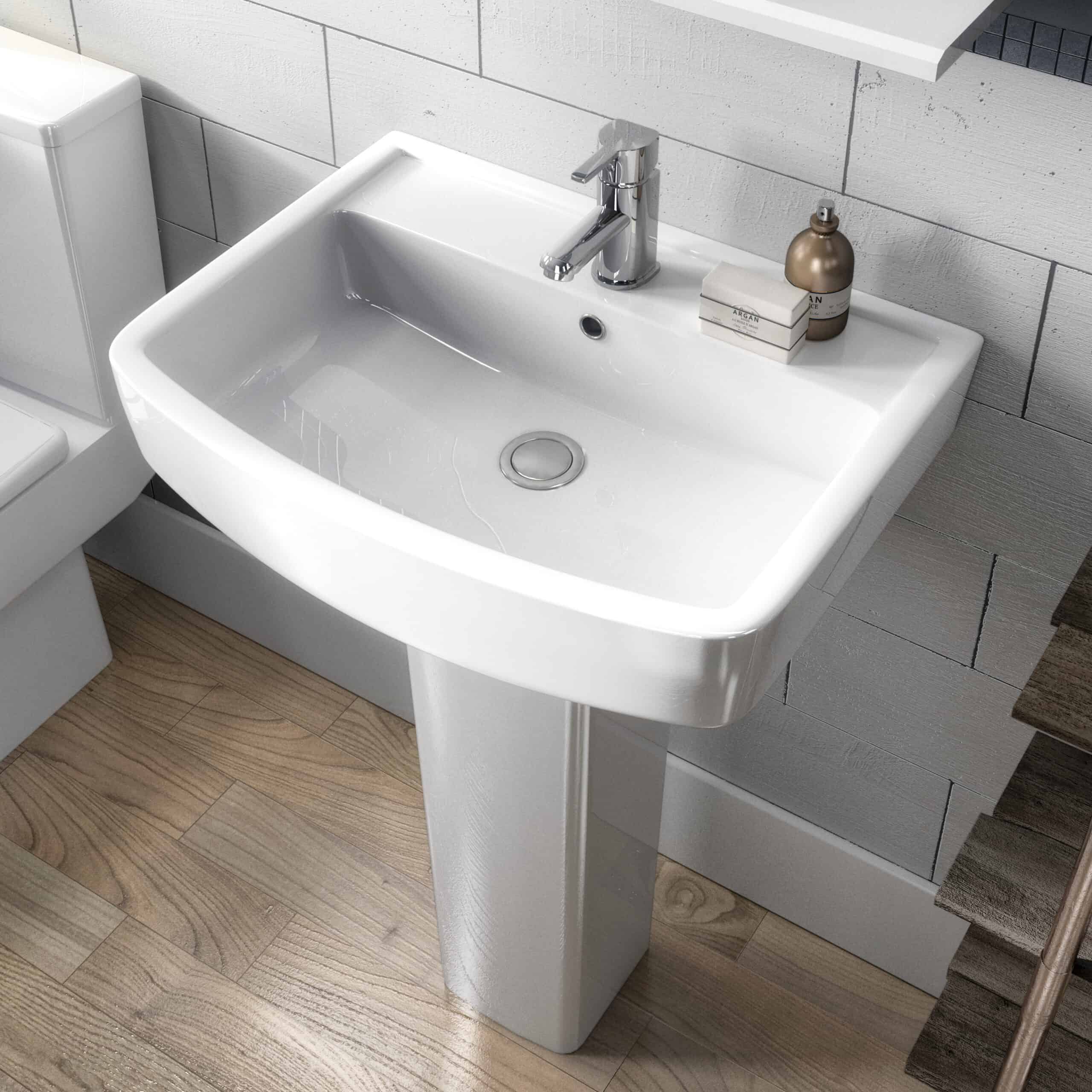 Sleek white bathroom sink with modern chrome tap, set against a textured white tiled wall, styled with minimal accessories for contemporary bathroom design.