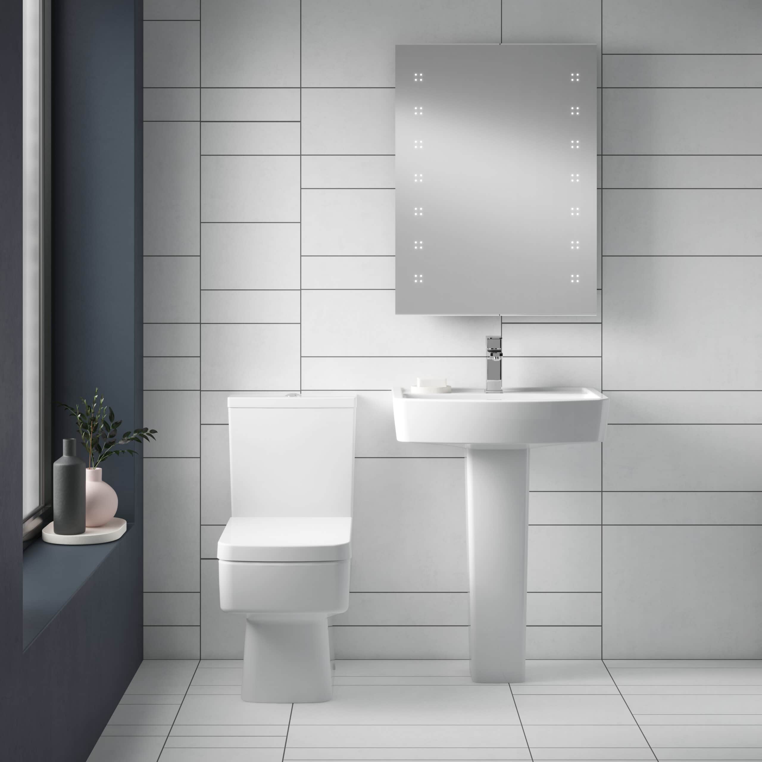 Sleek modern bathroom featuring a white toilet, pedestal sink with a large mirror, white tiled walls, and a minimalist design perfect for contemporary bathroom renovations.