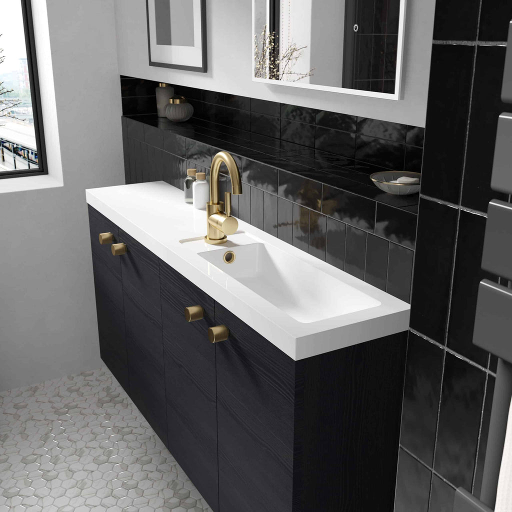 Golden bathroom faucet with matching cabinet handles and white sink in modern black and white bathroom decor.