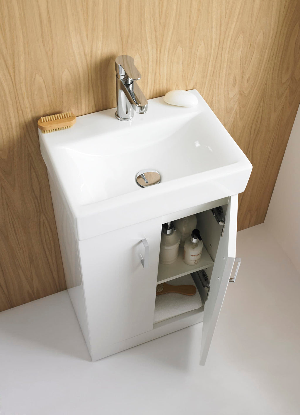 Compact white bathroom vanity with integrated sink, chrome faucet, wooden accents, and storage cabinet for bathroom essentials, showcasing modern bathroom design.