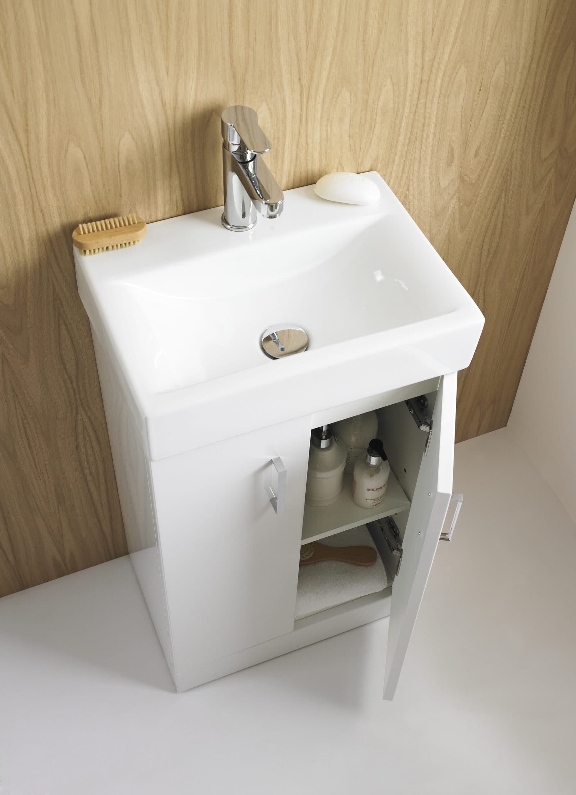 Compact white bathroom vanity with integrated sink, chrome faucet, wooden accents, and storage cabinet for bathroom essentials, showcasing modern bathroom design.