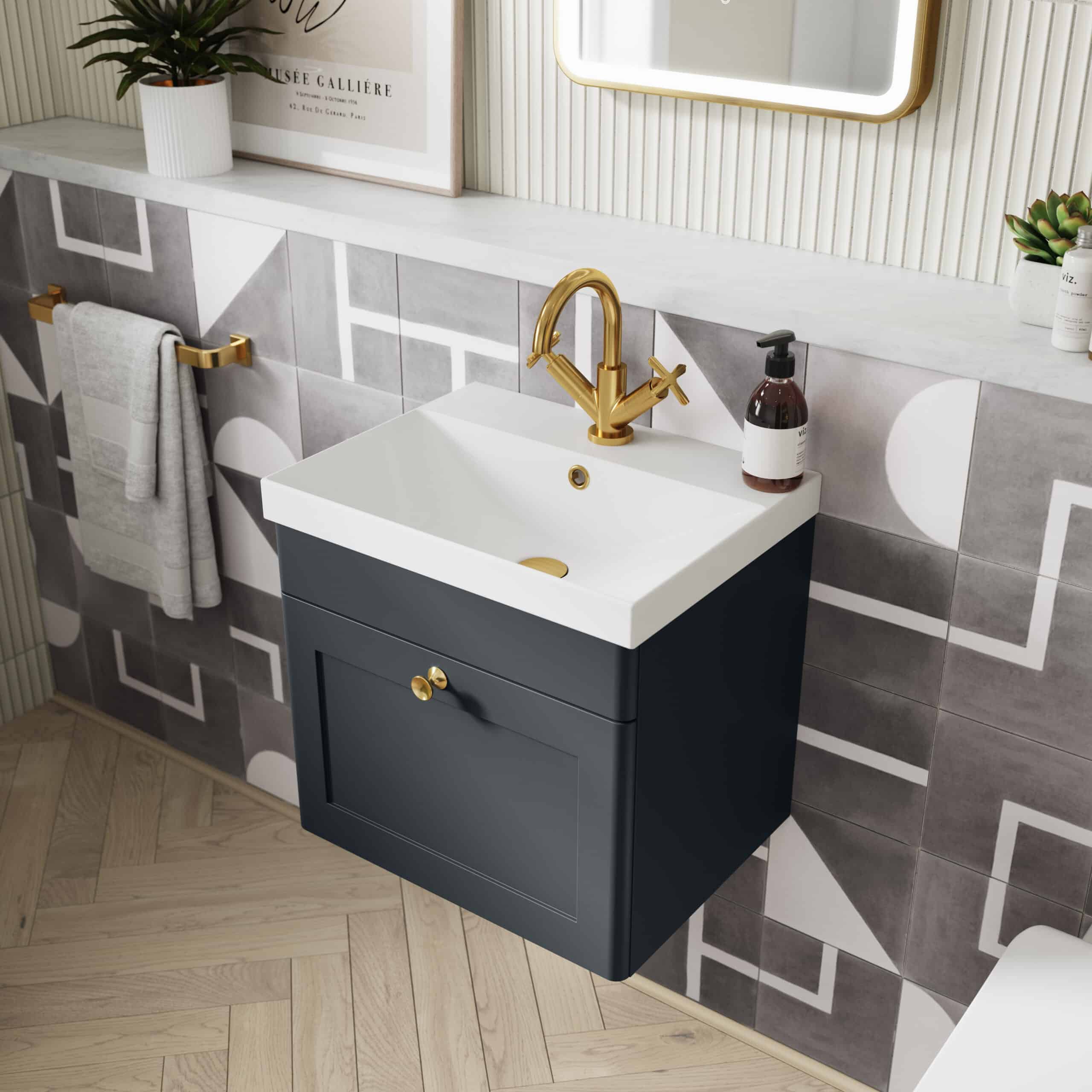 Elegant bathroom vanity with white ceramic sink, gold faucet, navy cabinet with gold hardware, and modern geometric tile wall. Perfect for stylish bathroom decor.