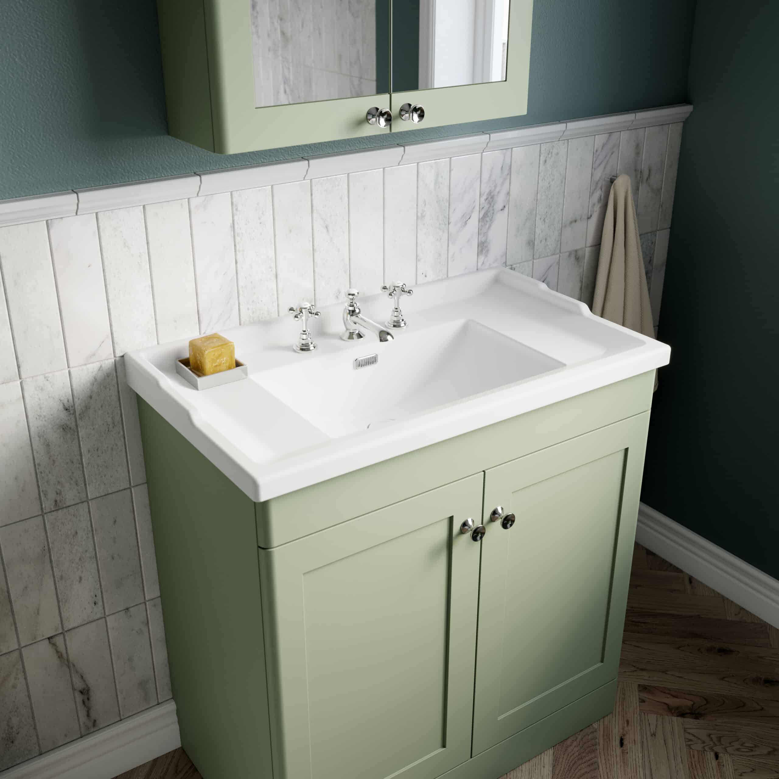 Luxurious green bathroom vanity with classic white porcelain sink, chrome taps, and marble tiling for a stylish, contemporary bathroom with high-quality fittings and elegant design.