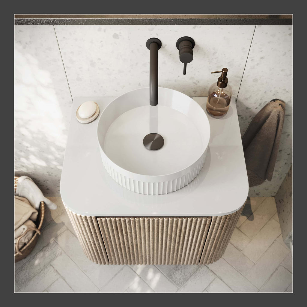Modern round bathroom sink with black matte tap on a white countertop, featuring a textured beige cabinet base, soap dispenser, and towel, ideal for contemporary bathroom design.