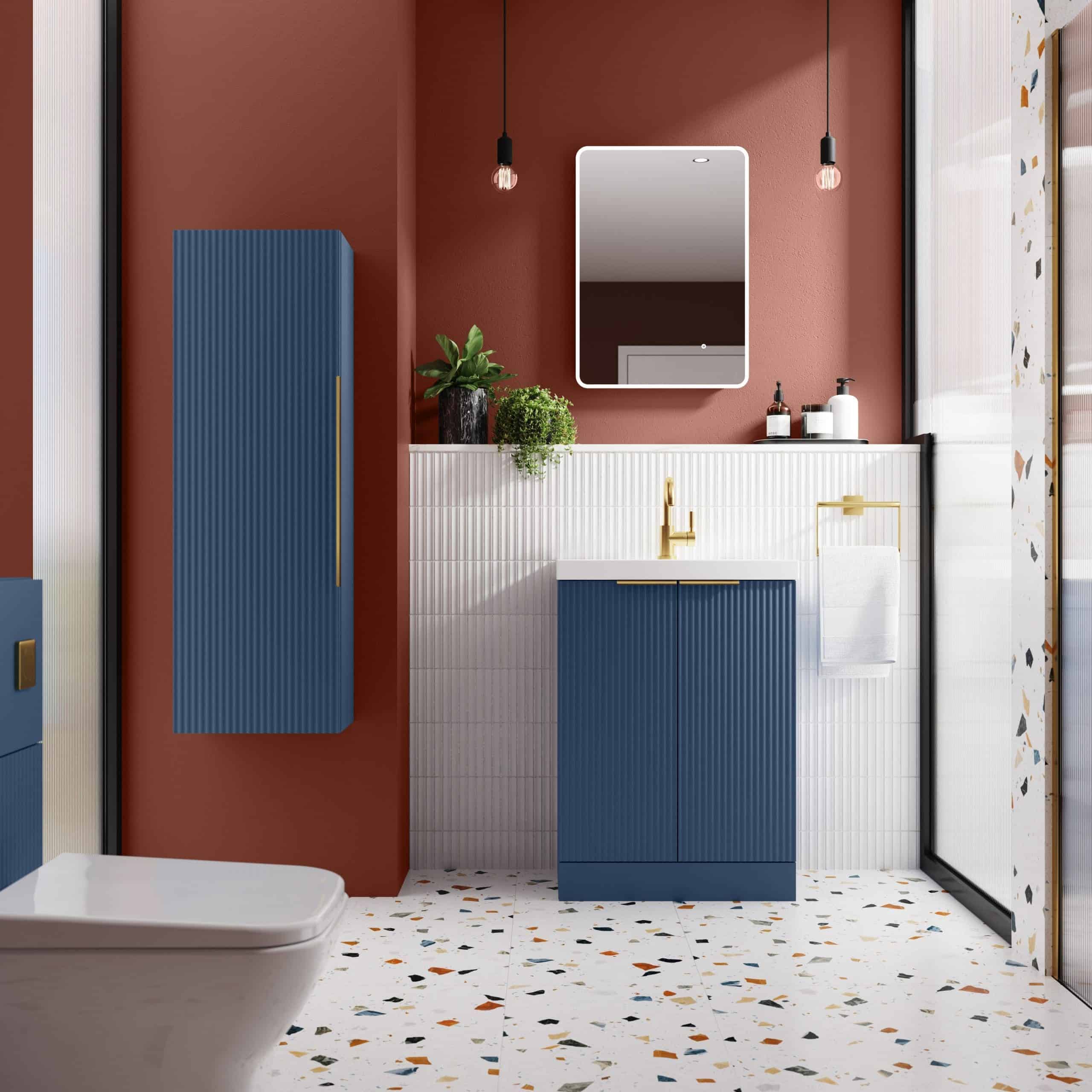 Stylish modern bathroom with blue vanity, white tiled wall, terrazzo flooring, gold fixtures, and decorative plants, creating an elegant and contemporary bathroom design.