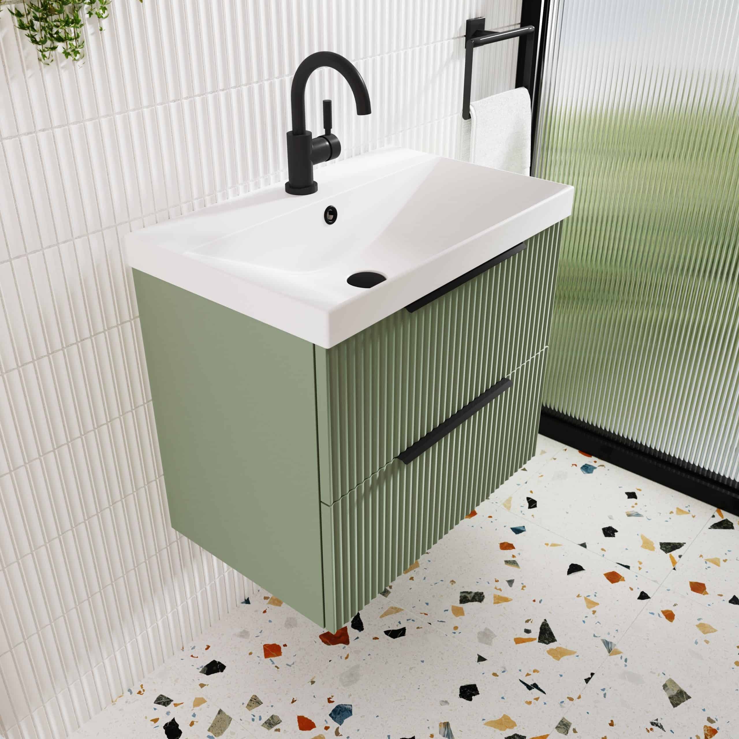 Contemporary green bathroom vanity with a white ceramic countertop and black fixtures, positioned against textured white wall tiles. Perfect for modern bathroom decor, combining style and functionality.