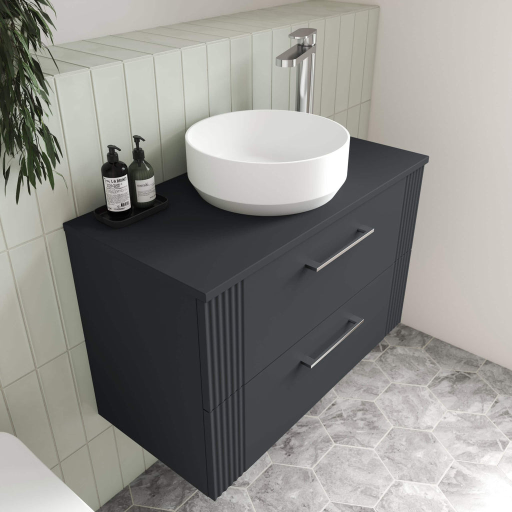 Deep grey bathroom vanity with a modern round white vessel sink and chrome tap, customised with black soap dispensers, ideal for contemporary bathroom decor.