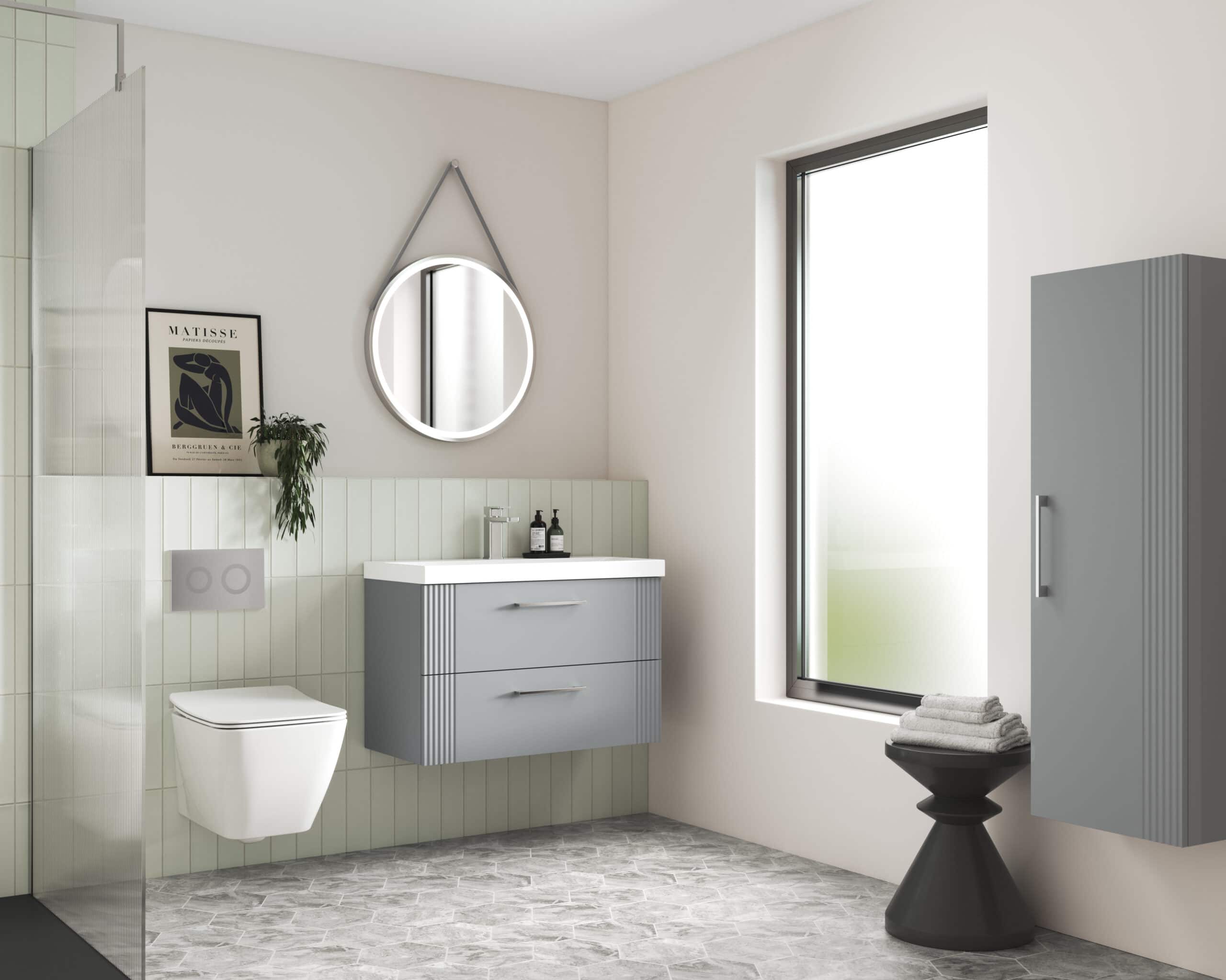 Sleek grey bathroom vanity with a white sink, modern round mirror with LED lighting, wall-mounted toilet, tall storage cabinet, and minimalist decor in a contemporary bathroom setting.