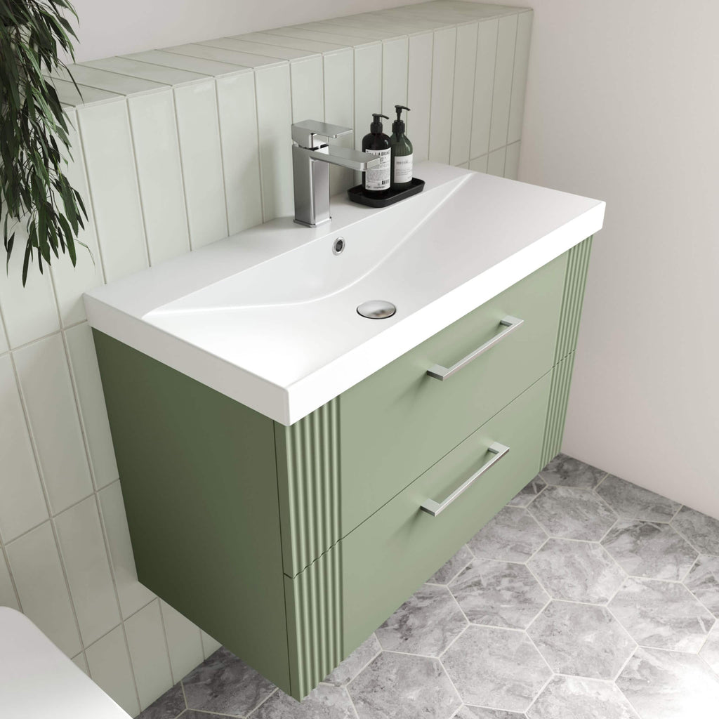 Sleek green bathroom vanity with built-in sink and modern chrome handles, set against a tiled wall with a decorative ceramic floor, perfect for contemporary bathroom designs.
