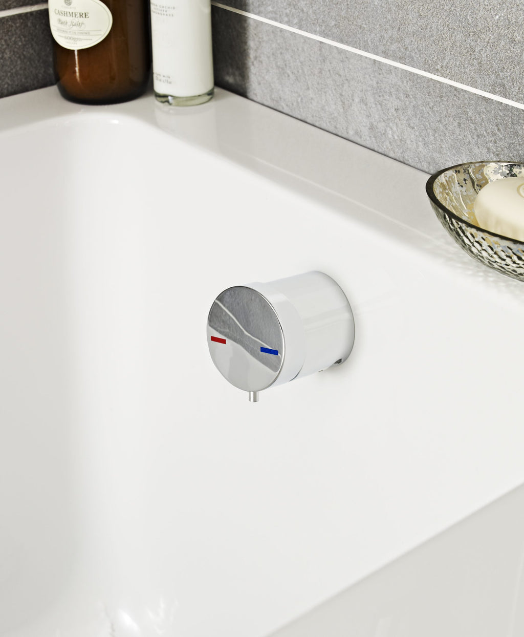 Sleek thermostatic mixing valve in a modern bathroom setting for precise temperature control, mounted on a white bathtub with bathroom essentials in the background.