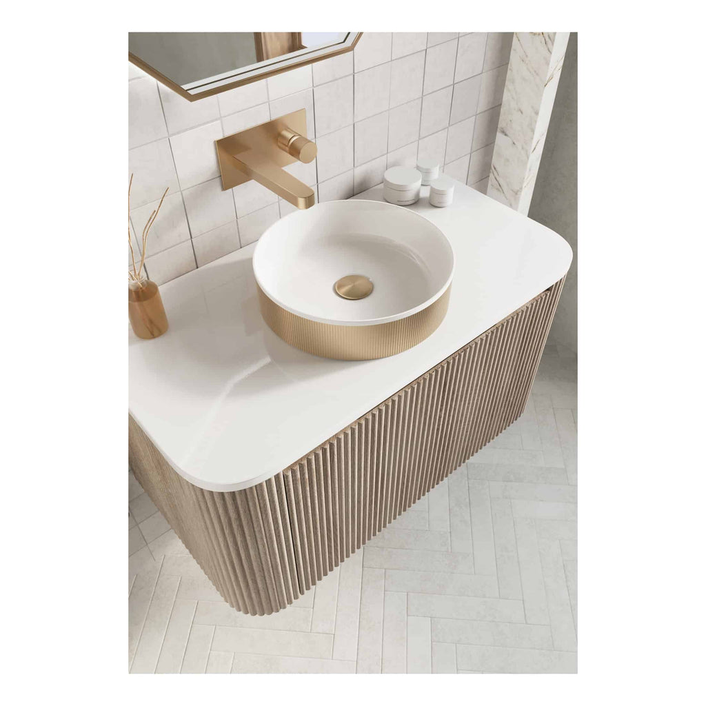 Sleek modern bathroom vanity with a round white vessel sink featuring a gold base, wall-mounted gold faucet, and minimalist decor, showcasing luxury bathroom design.
