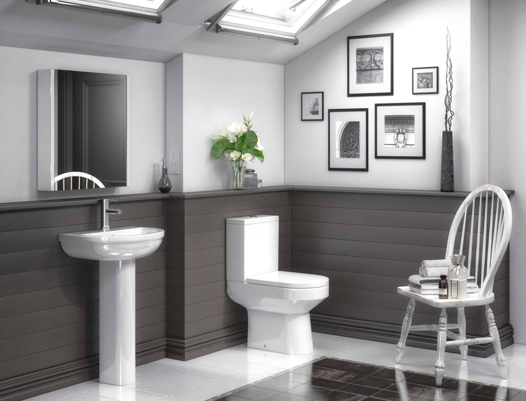 Luxurious bathroom with modern white toilet, pedestal sink, grey wall paneling, decorative framed art, and natural light from skylights, showcasing elegant and contemporary bathroom design.