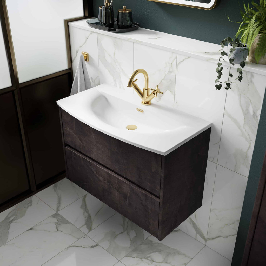 Polished brass bathroom mixer tap and elegant white ceramic sink with dark wood vanity in a modern bathroom setting.