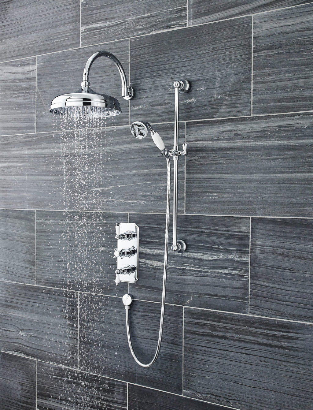 Shower system with rain shower head and handheld shower in a modern bathroom with grey tiled wall, showcasing luxury bathroom fixtures.
