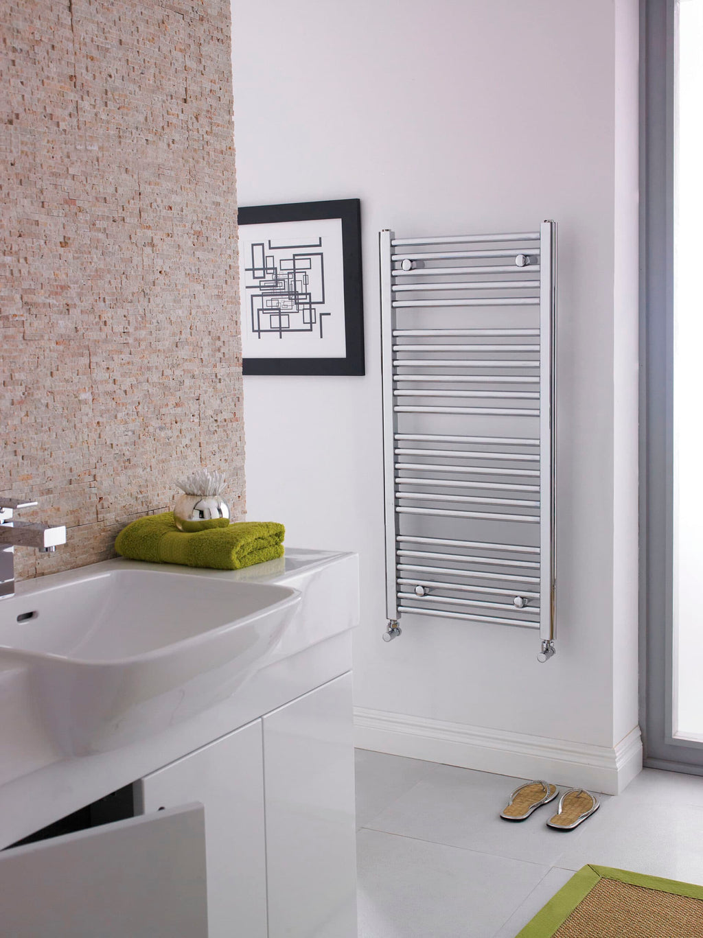 Sleek modern bathroom with white vanity, textured brick accent wall, heated towel rail, framed artwork, and green accents, showcasing contemporary bathroom design and fixtures.