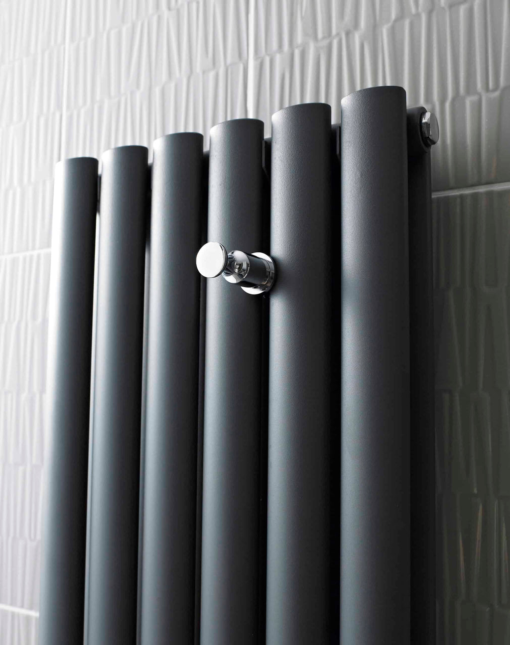 Radiator in modern bathroom with sleek, black matte finish and chrome control valve, ideal for contemporary bathroom heating solutions.