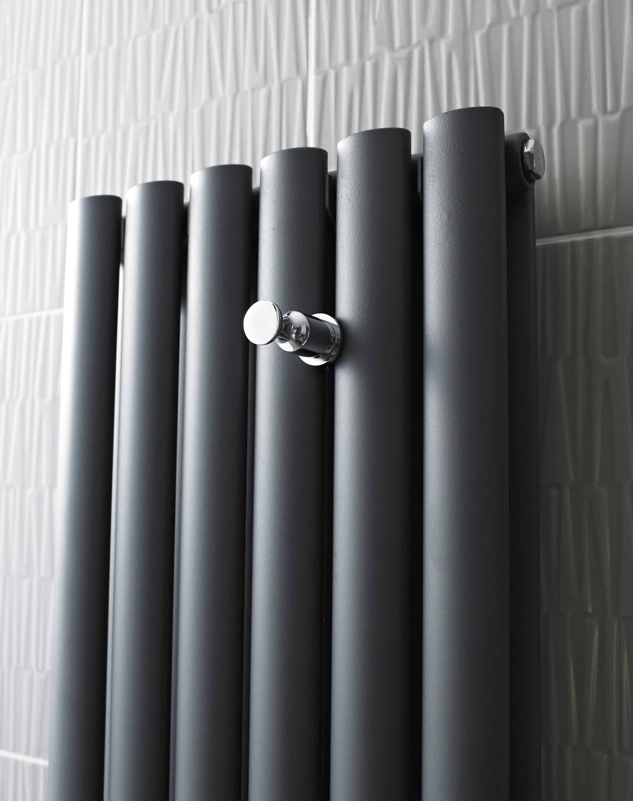 Radiator in modern bathroom with sleek, black matte finish and chrome control valve, ideal for contemporary bathroom heating solutions.