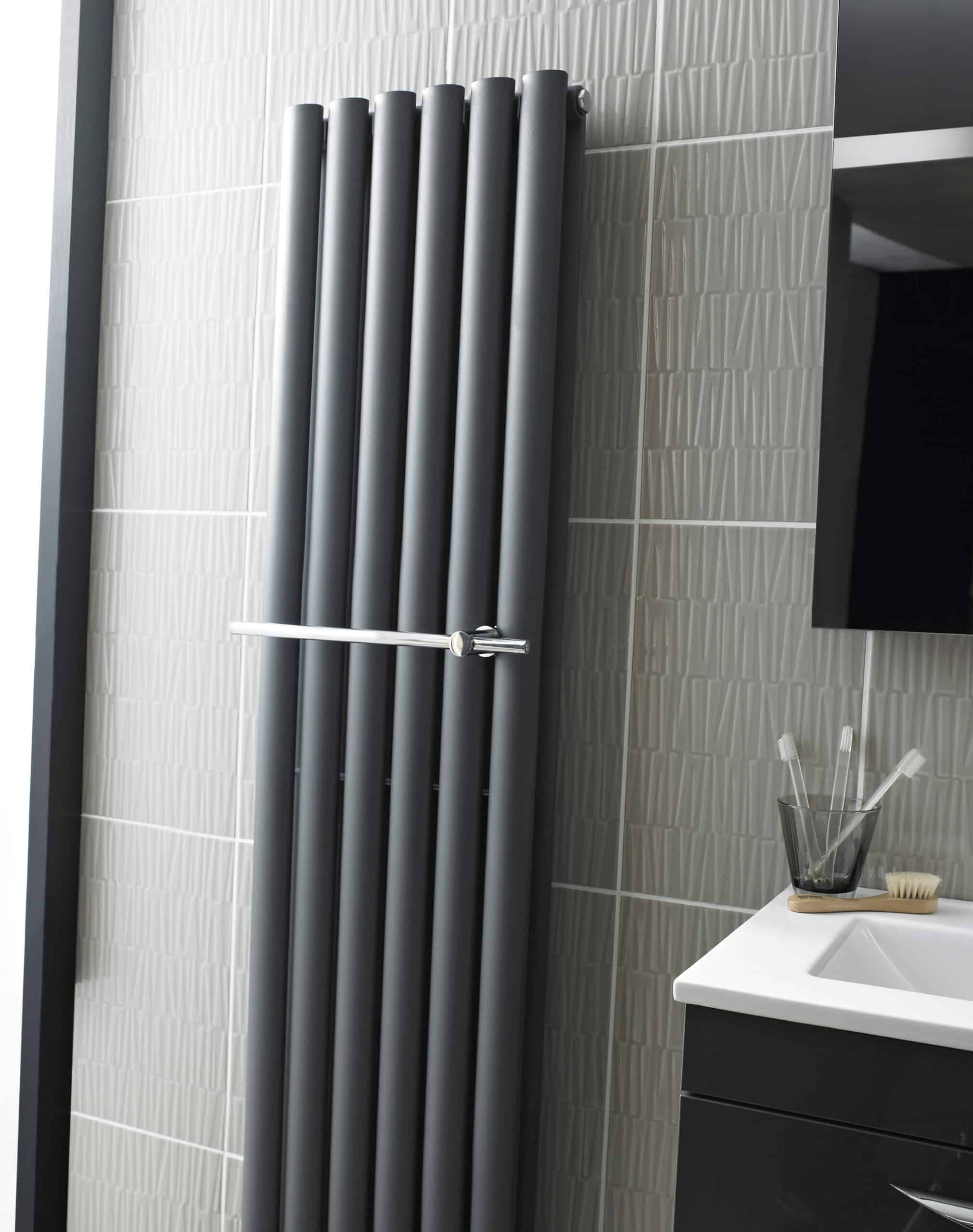 Metalic vertical radiators in modern bathroom with wall tiles and bathroom vanity.