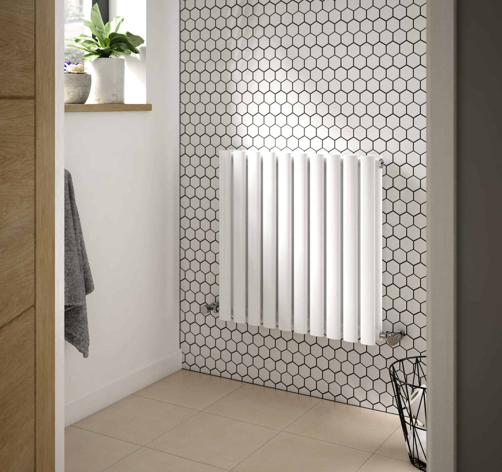 Modern white radiator against a hexagon-tiled bathroom wall, with natural light from a nearby window, minimalist decor, and wooden accents, perfect for contemporary bathroom heating solutions.