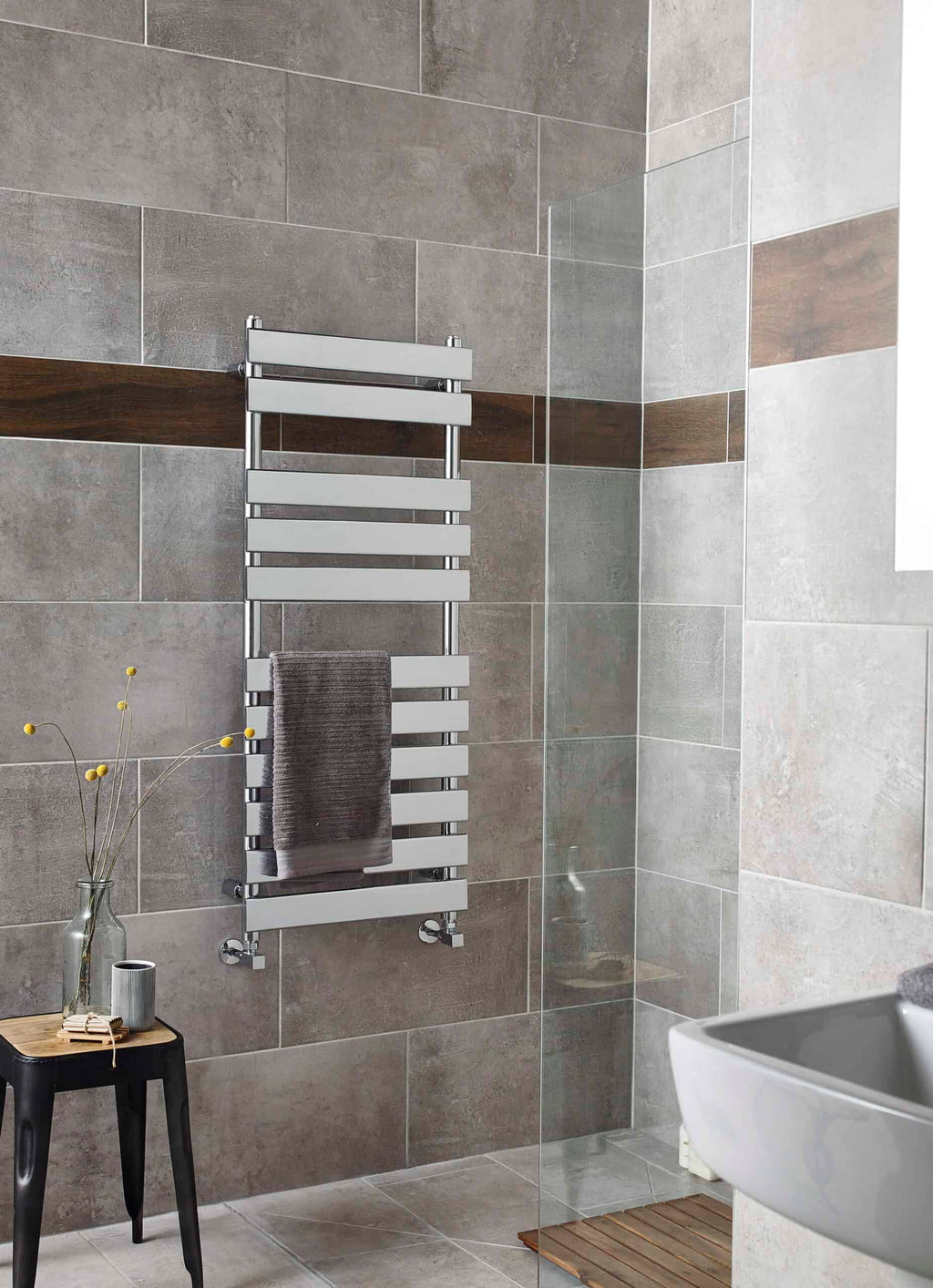 Modern heated towel rail in a contemporary bathroom with grey and brown tiled walls, adding comfort and style.