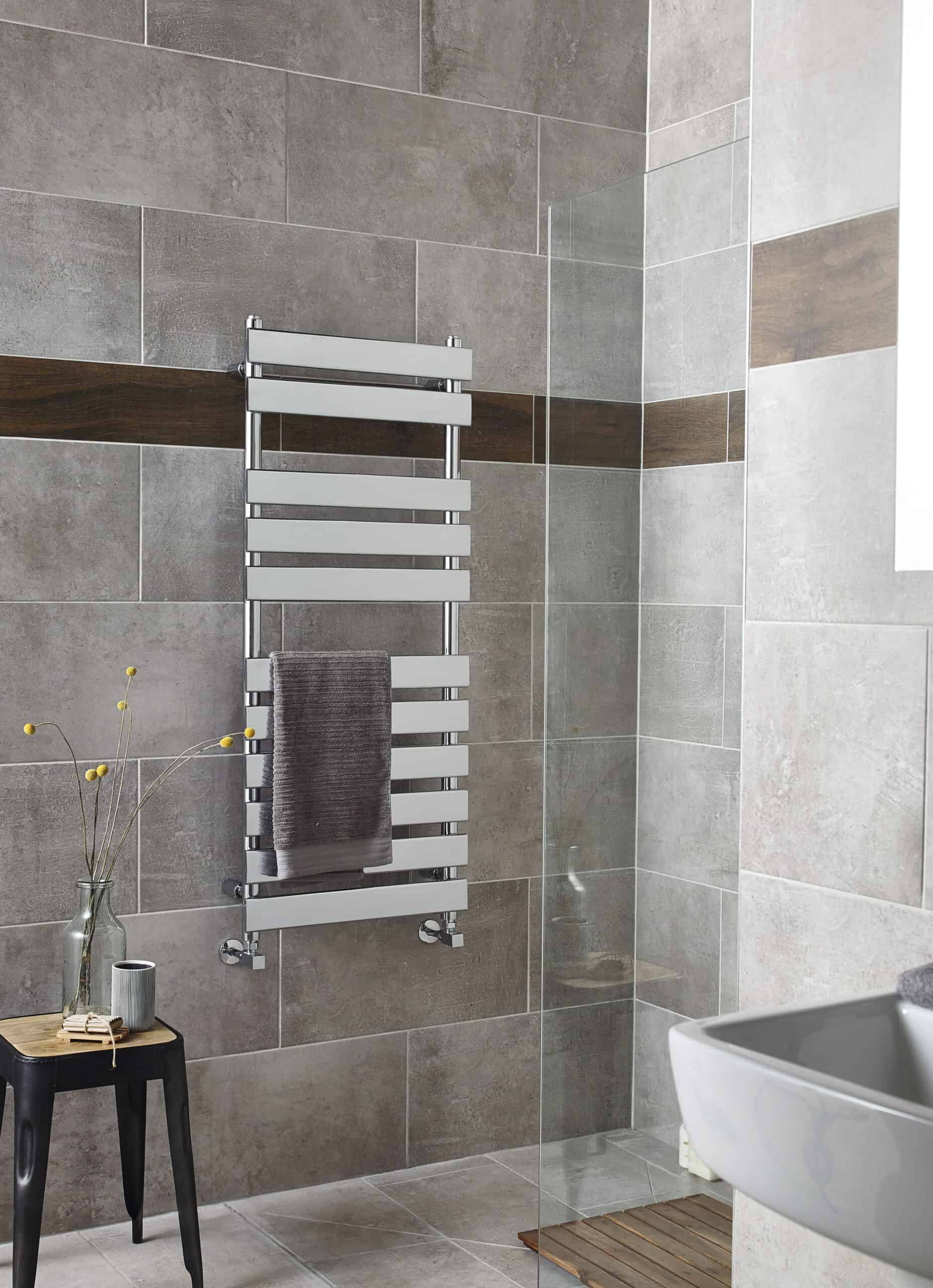 Modern heated towel rail in a contemporary bathroom with grey and brown tiled walls, adding comfort and style.