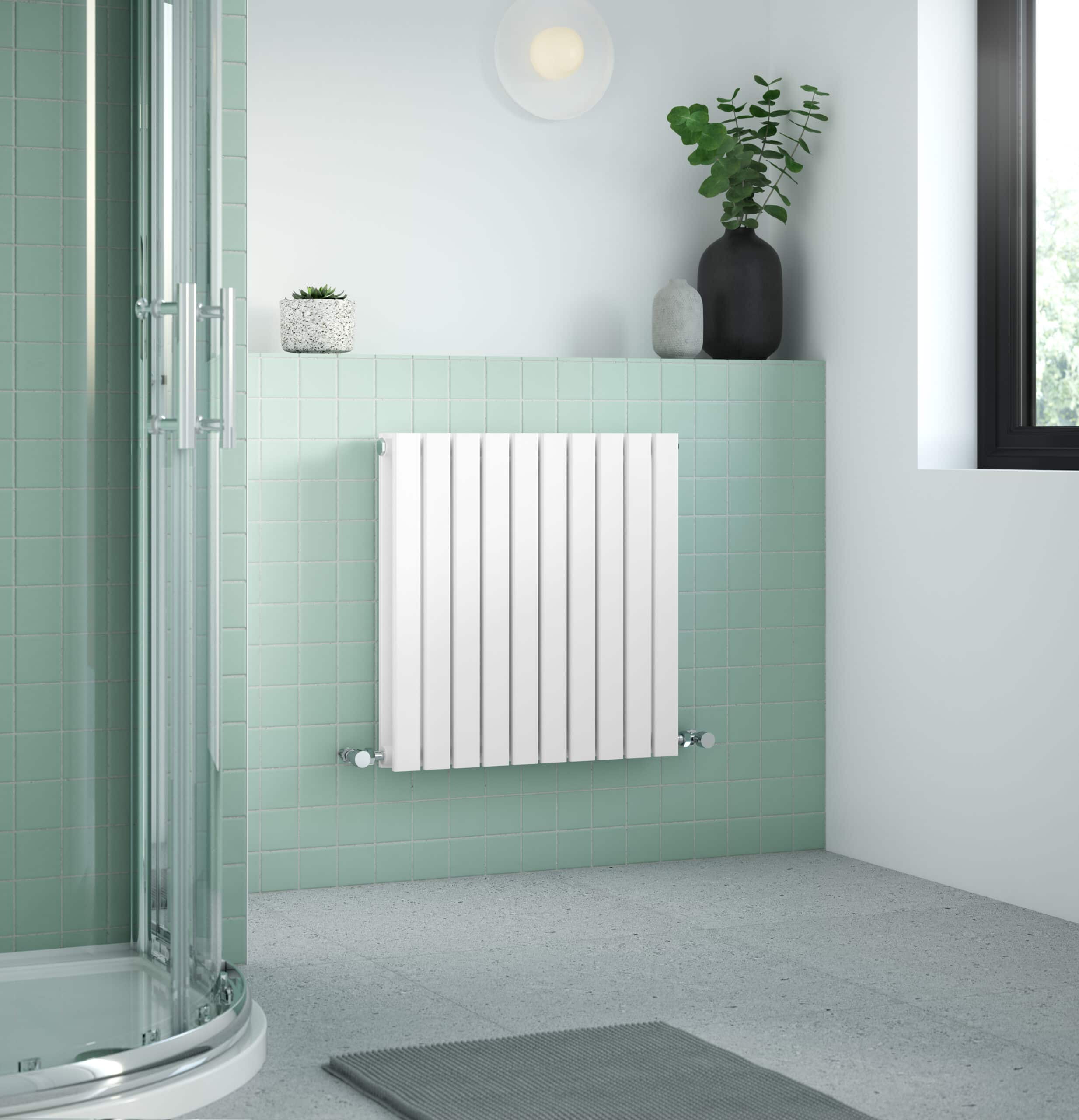 Modern bathroom with green tiled walls, white radiator, glass shower enclosure, and decorative vases with green plants, creating a stylish and functional space.