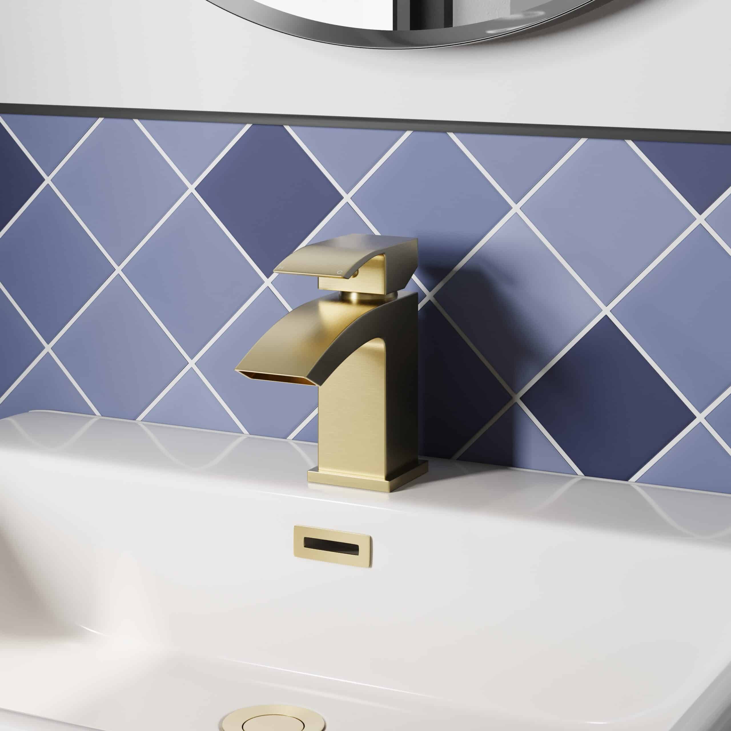 Sleek gold bathroom tap with modern design on a white sink, blue diamond-patterned tiles in the background, showcasing contemporary bathroom fixtures from Bubly Bathrooms.