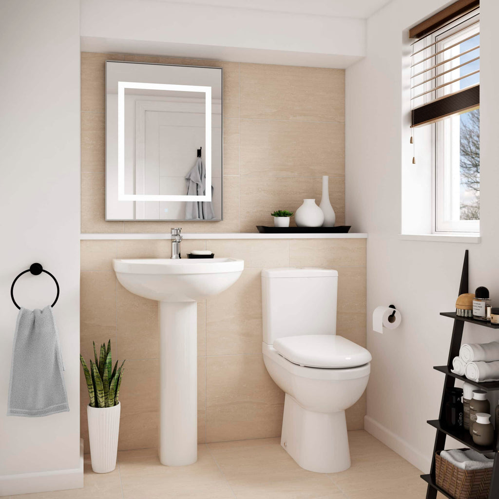 Modern minimalist bathroom featuring a white porcelain toilet and sink, beige tiled wall, decorative vases, and stylish storage with towels and toiletries. Bright natural light from a nearby window enhances the space.