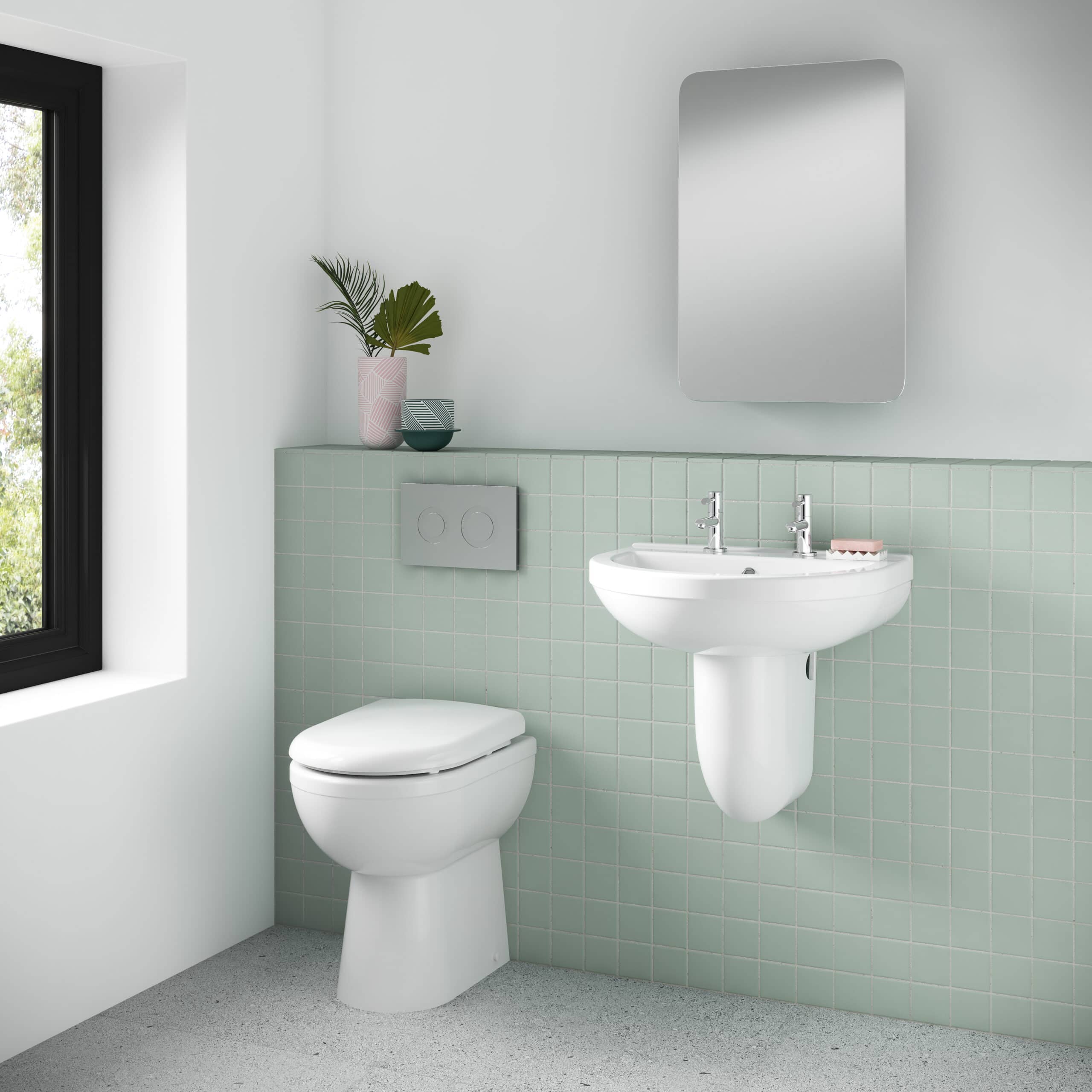Sleek white bathroom with wall-mounted toilet and pedestal sink, featuring modern chrome fixtures, pastel green tiling, and stylish decor for a minimalist and contemporary look.