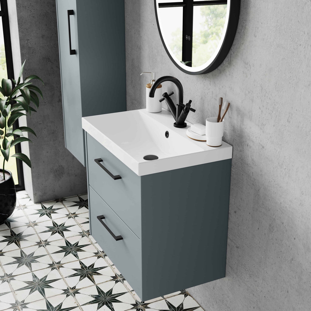 Sleek blue bathroom vanity with white ceramic sink, black tap, and mirror, set against a concrete wall with decorative tiled floor, showcasing modern bathroom design and fixtures.