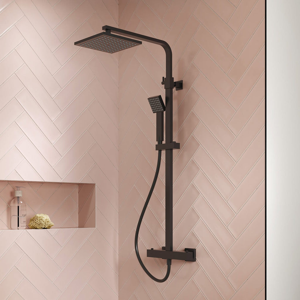 Modern black shower head set with overhead rain shower and handheld spray on pink tiled bathroom wall.