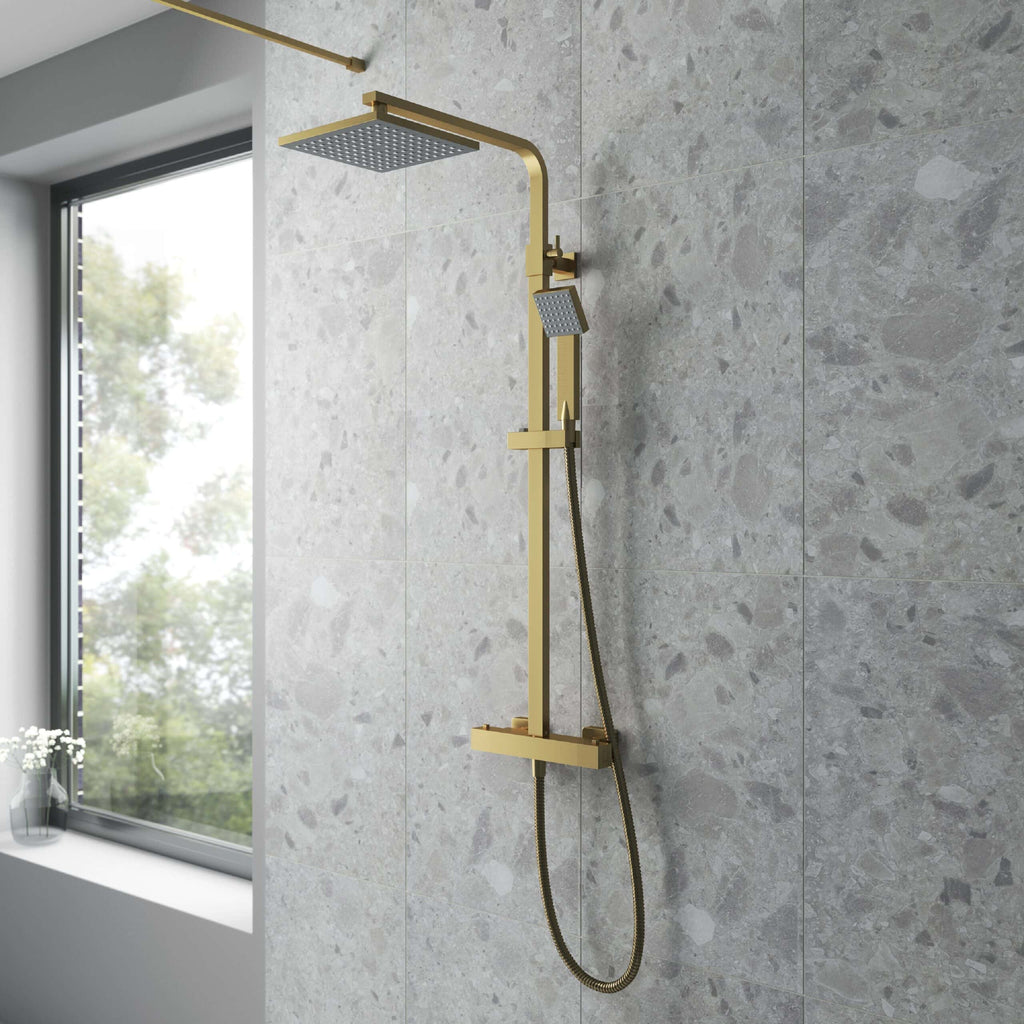 Shower rain head with gold finish in a modern bathroom, minimalist design, grey tiled wall, natural light from window, luxury bathroom fixtures.