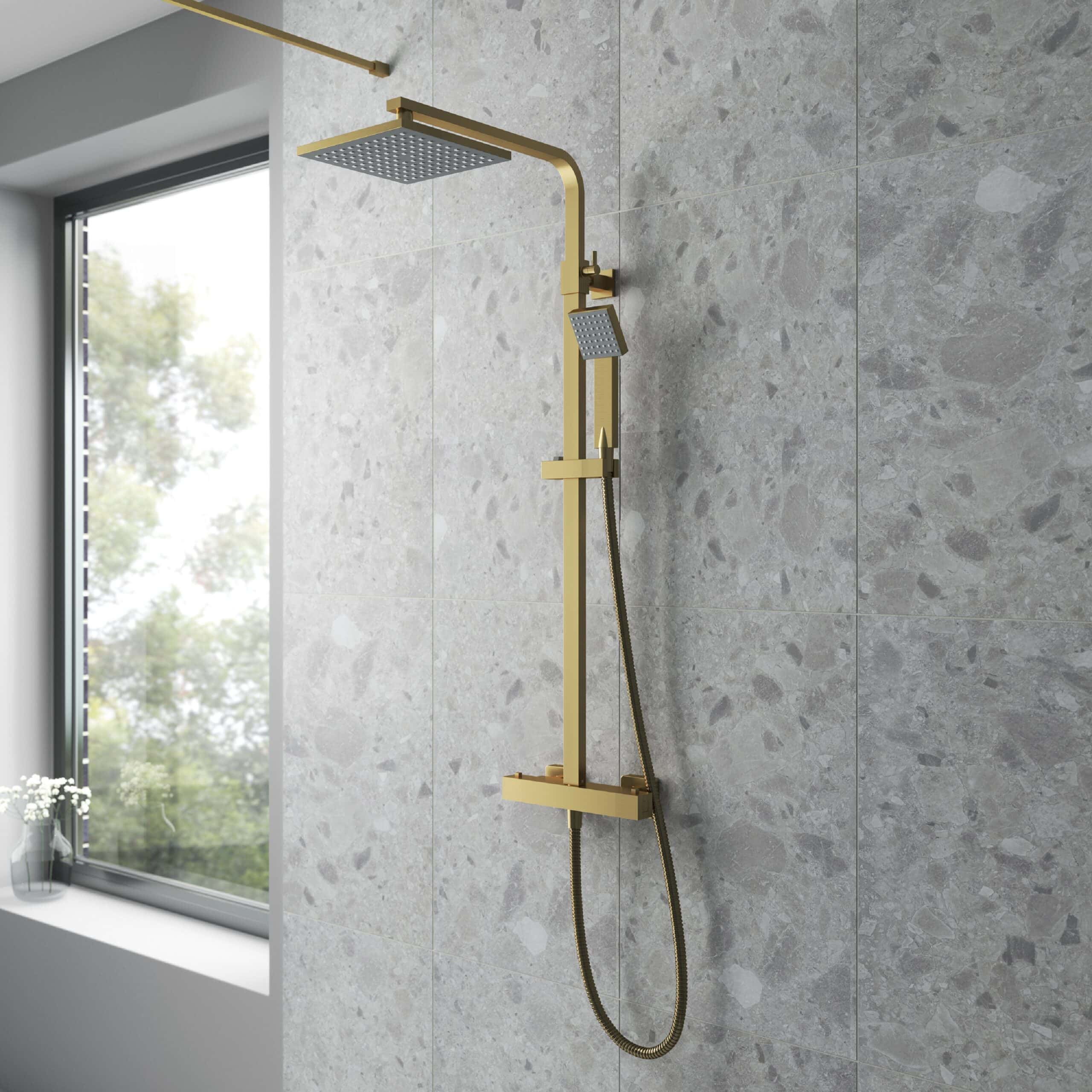 Shower rain head with gold finish in a modern bathroom, minimalist design, grey tiled wall, natural light from window, luxury bathroom fixtures.