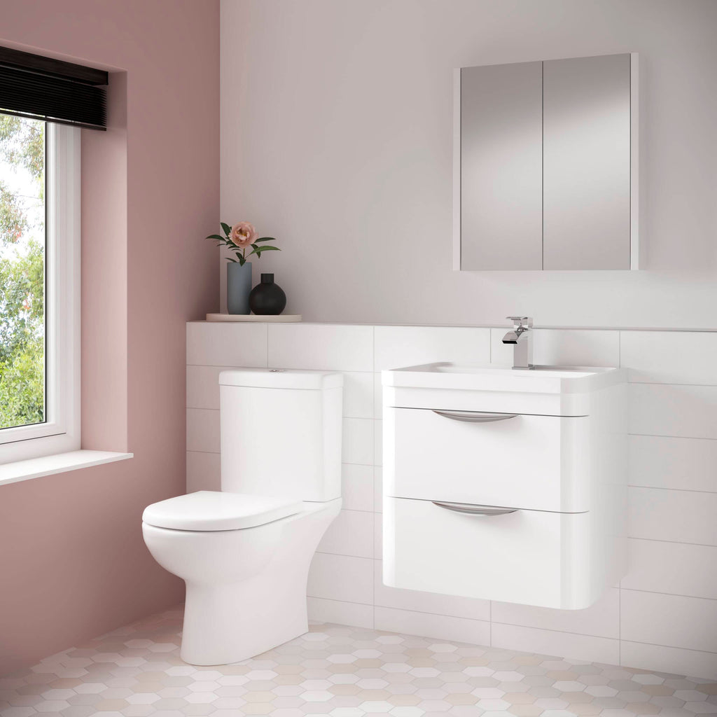 Contemporary white bathroom sink unit with storage drawers, toilet, and wall-mounted mirror cabinet in a modern, minimalist design within a bright, airy bathroom setting.