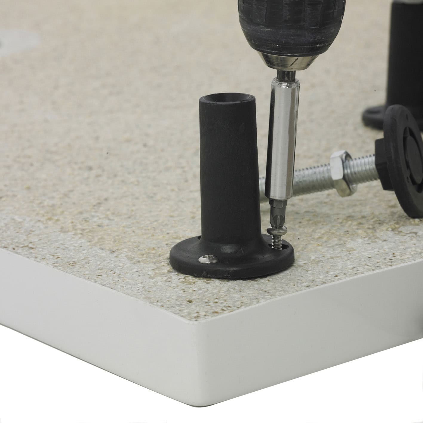 Screwdriver installing adjustable bathroom furniture stability foot on bathroom countertop.
