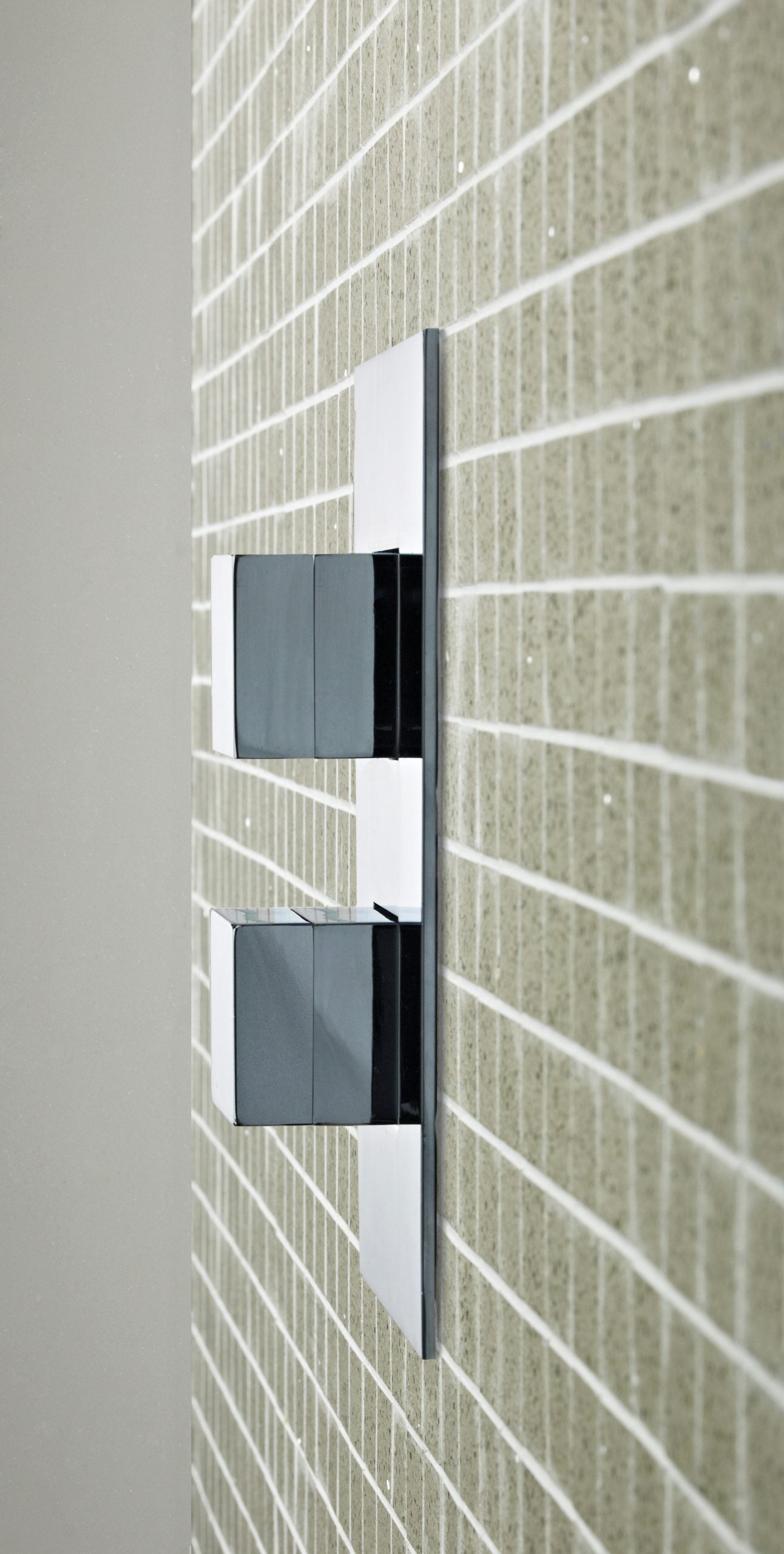 Sleek modern flush buttons for bathroom cisterns mounted on beige tiled wall, designed for stylish and functional bathroom plumbing solutions.