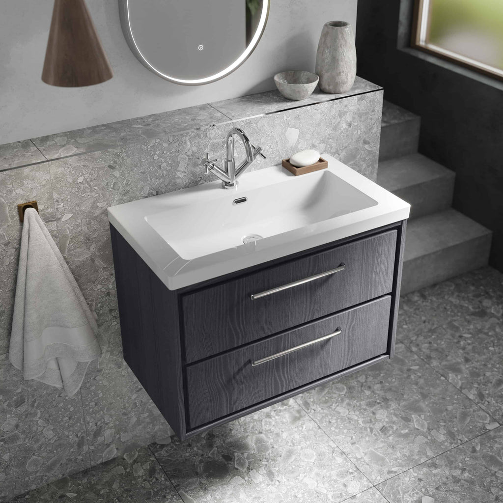 Modern vanity bathroom sink with black wooden cabinet featuring two drawers, sleek chrome handles, and a white ceramic basin, set against a grey textured wall with decorative vases and a mirror, ideal for contemporary bathroom design.