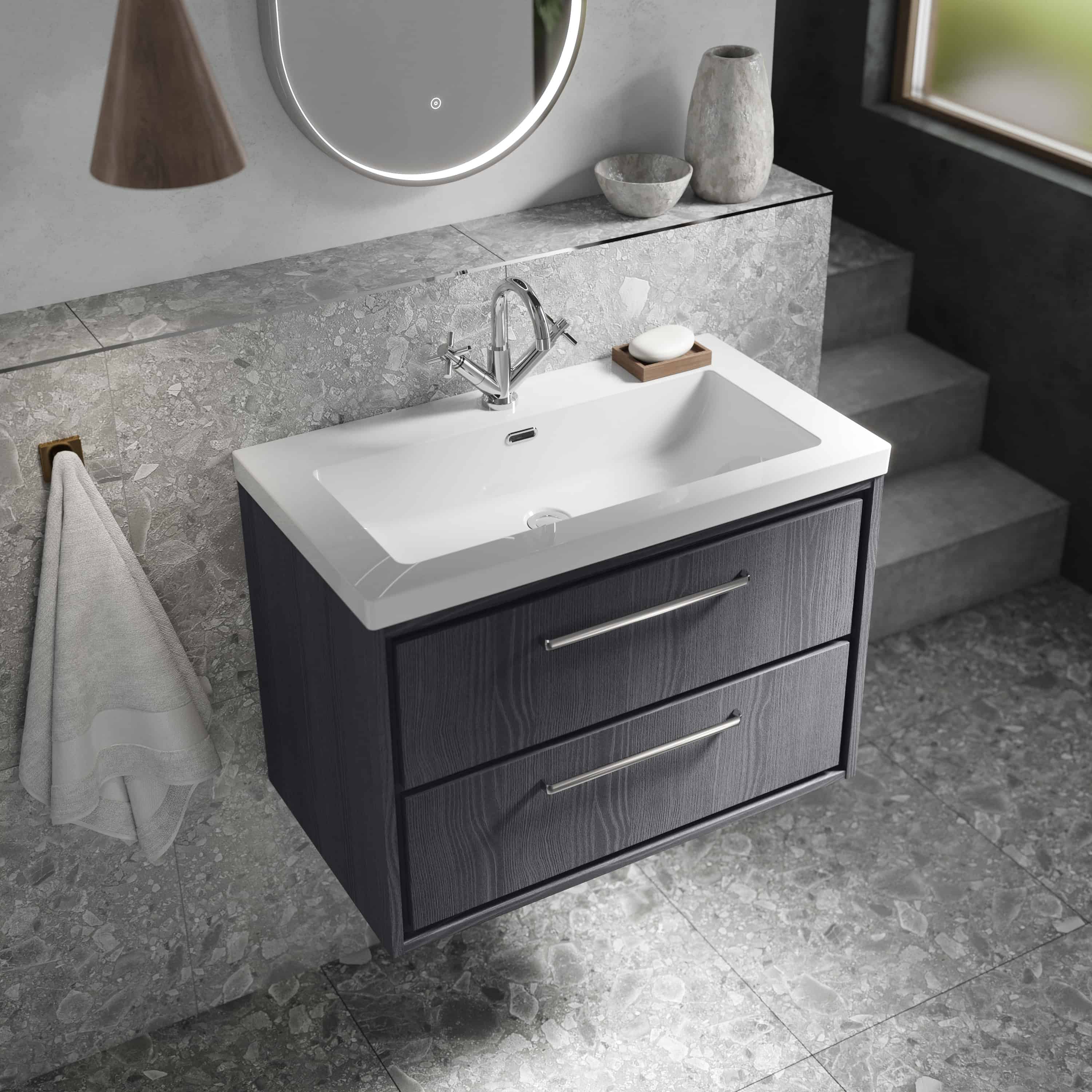 Modern vanity bathroom sink with black wooden cabinet featuring two drawers, sleek chrome handles, and a white ceramic basin, set against a grey textured wall with decorative vases and a mirror, ideal for contemporary bathroom design.