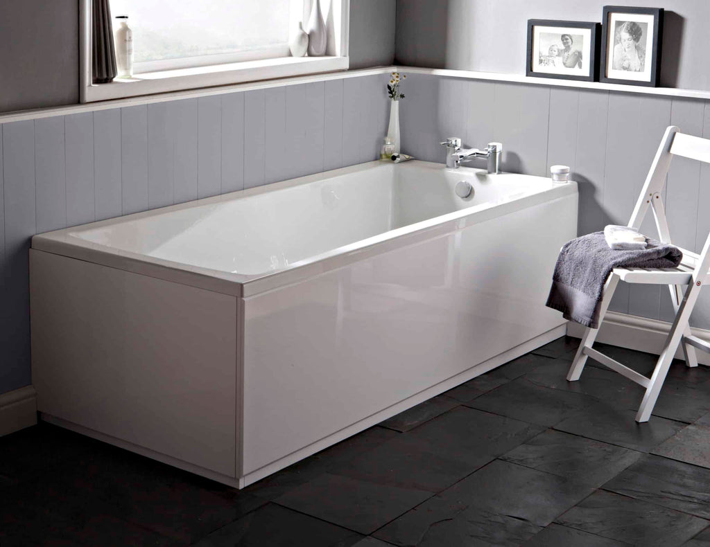 White modern bathtub in a contemporary bathroom setting with grey wall cladding and black slate flooring, featuring a white wooden chair with towels, and black-and-white framed photos on the wall.