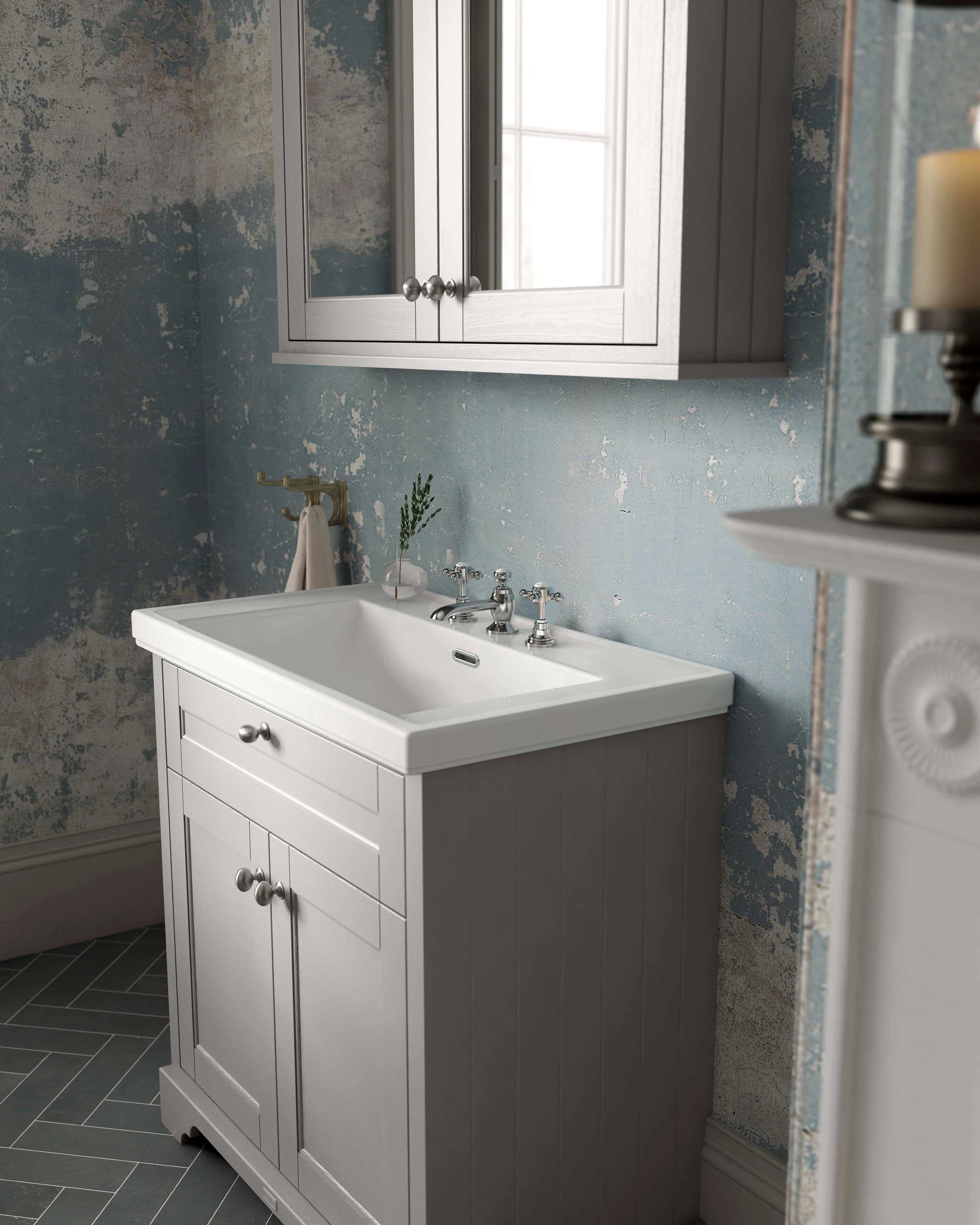 Elegant white bathroom vanity with traditional chrome fixtures, designed for classic bathroom decor, featuring a large mirror cabinet, situated against a textured blue wall with vintage charm.