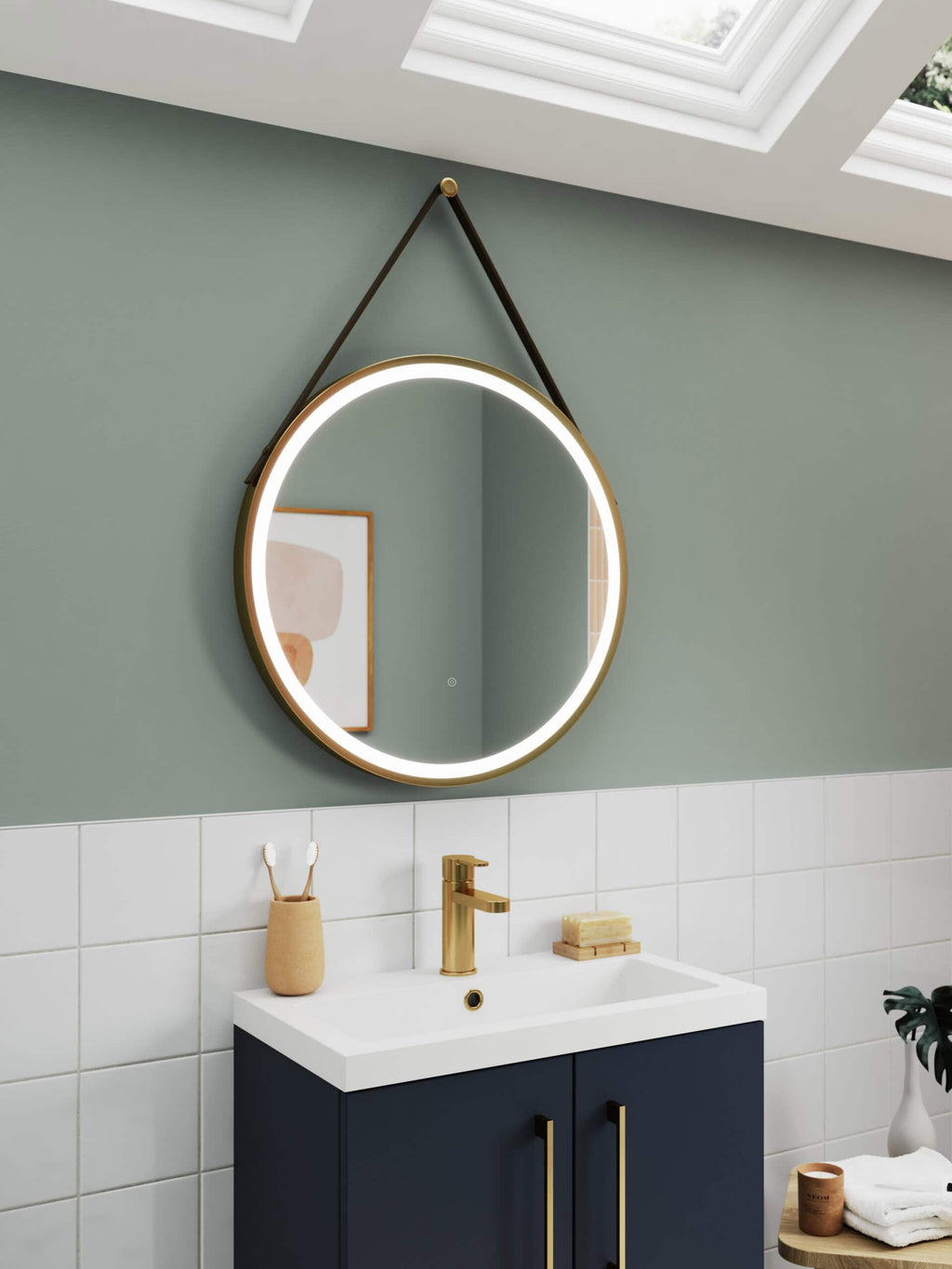 Sleek round mirror with LED lighting hanging above a modern navy bathroom vanity with gold fixtures, in a stylish and contemporary bathroom setting.