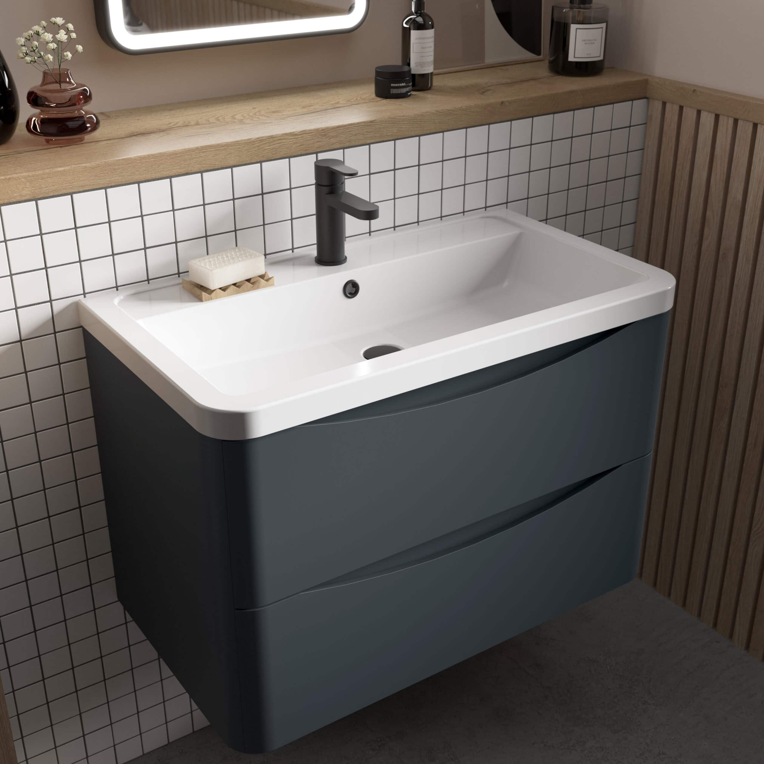 Sleek modern bathroom vanity with a white basin, black tap, and smooth grey drawers, set against a tiled wall with wooden accents, perfect for contemporary bathroom design.
