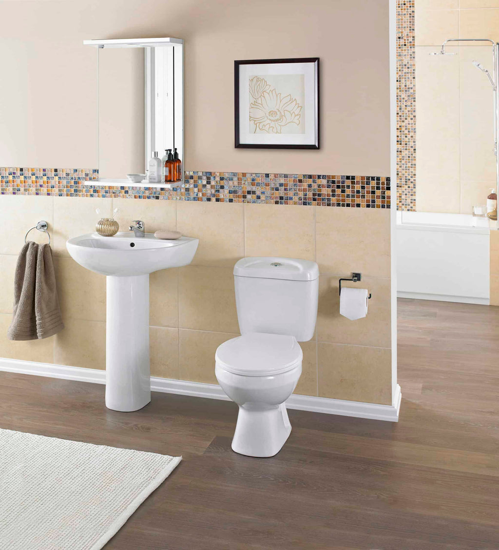 Modern bathroom with white ceramic toilet and pedestal sink, beige tiles with mosaic border, and bath area with shower, showcasing stylish and functional bathroom fixtures.