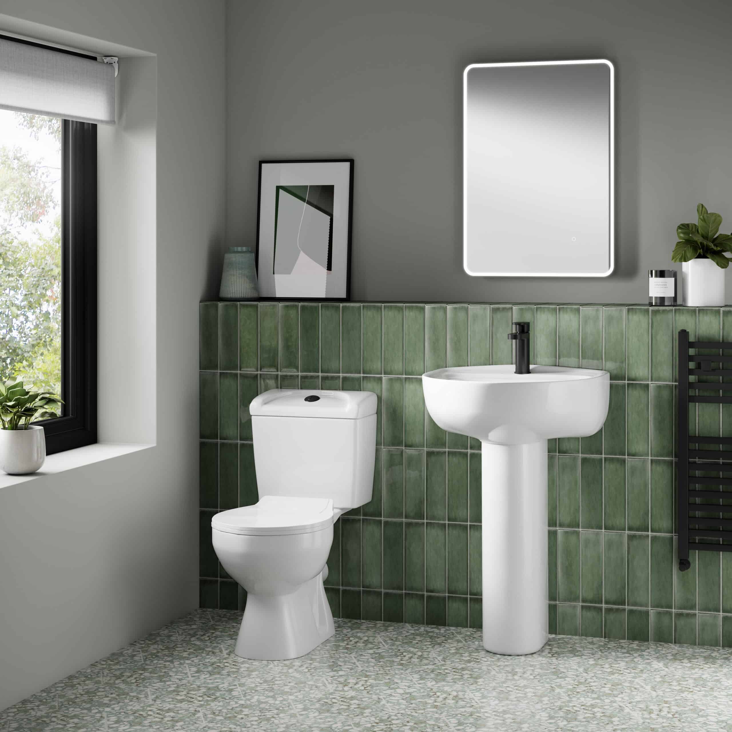 Modern bathroom with white toilet and pedestal sink, green tiled wall, LED-lit mirror, and a large window with natural light, showcasing stylish and functional bathroom design.