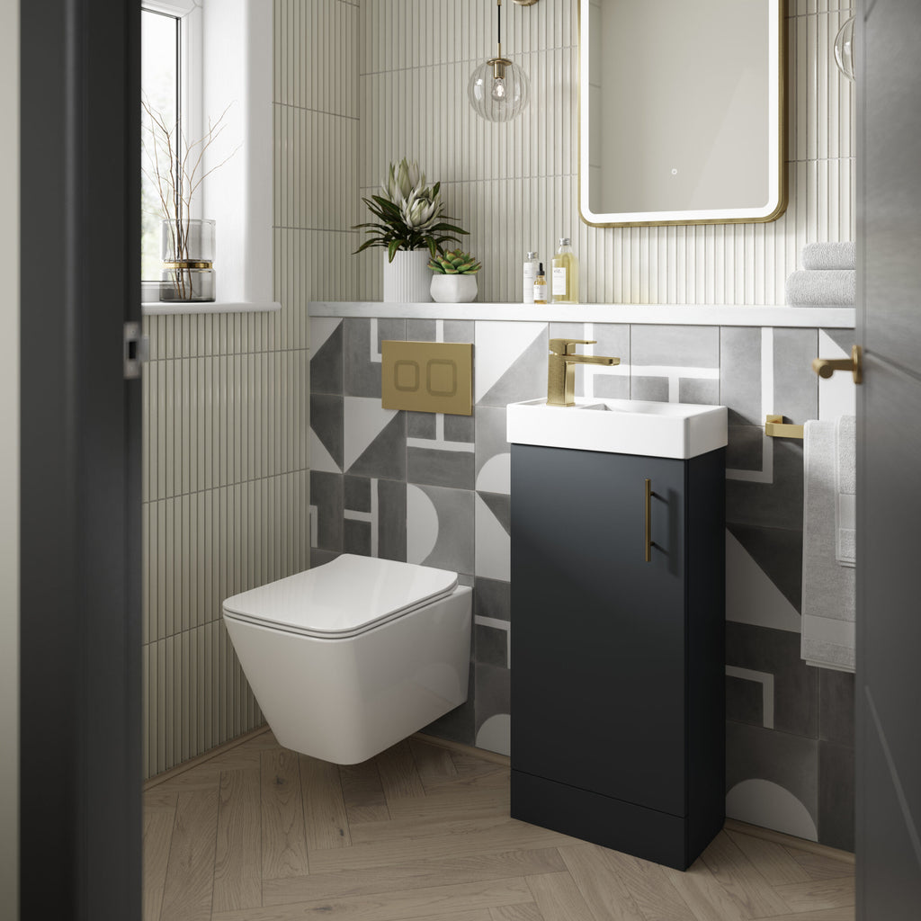 White modern bathroom with wall-mounted toilet, black vanity with gold hardware, geometric tile accents, and contemporary decor, showcasing stylish bathroom design and fittings.