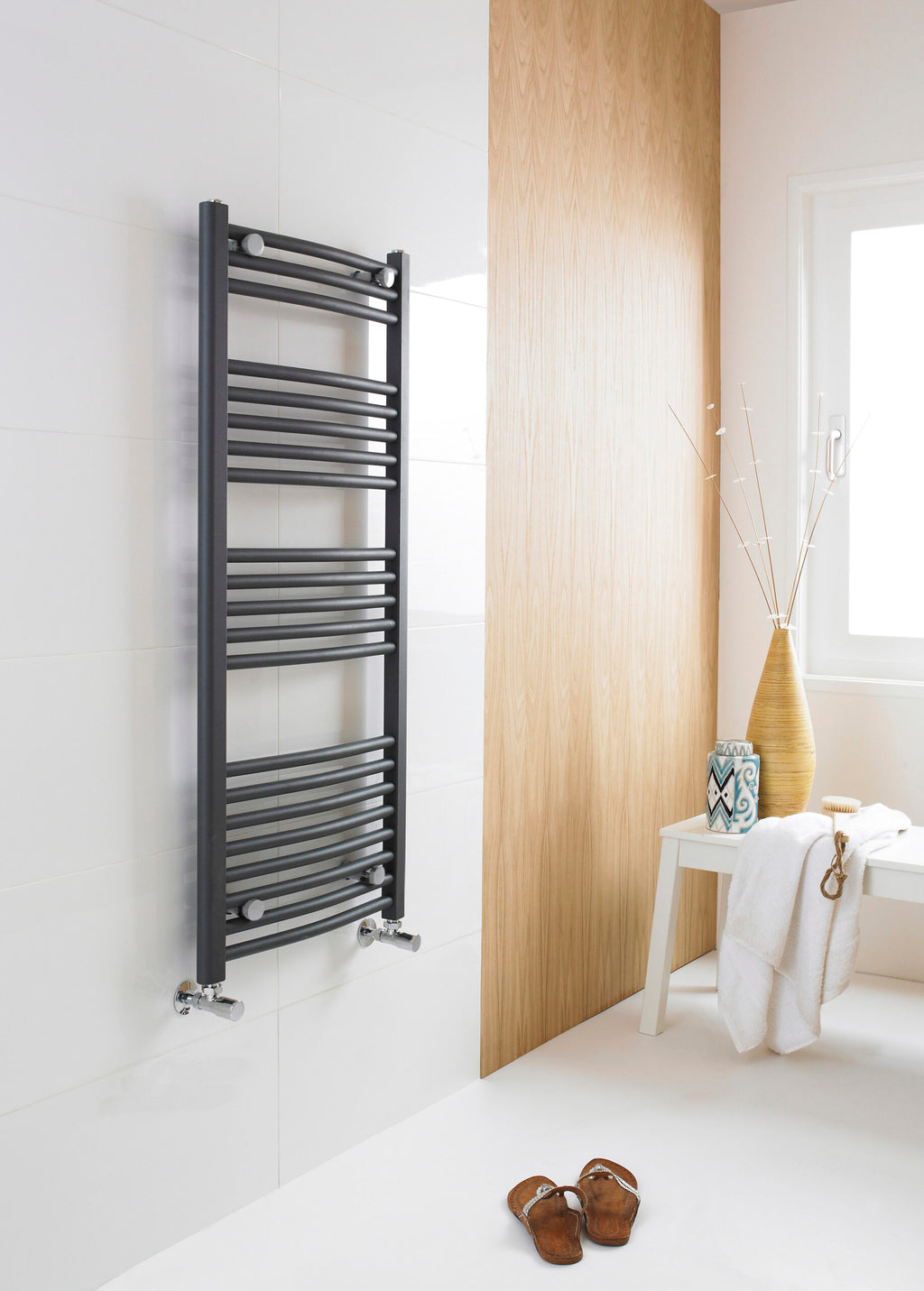Sleek black towel radiator in modern bathroom with white tiled wall and natural wooden panel, minimalist decor, and drying towel; stylish heated towel rail for contemporary bathrooms.