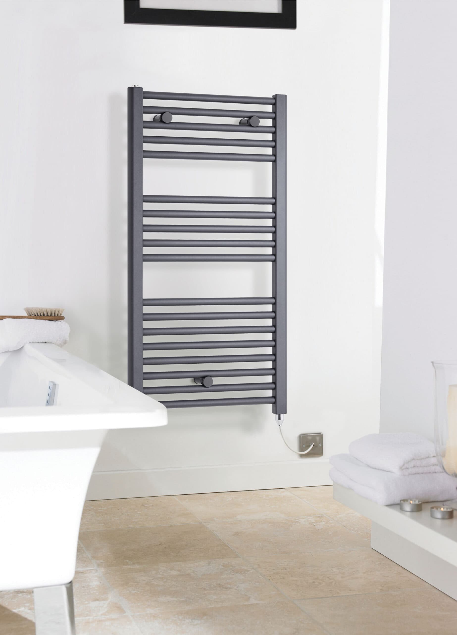 Warm grey heated towel rail mounted on a white bathroom wall for towel drying and heating.